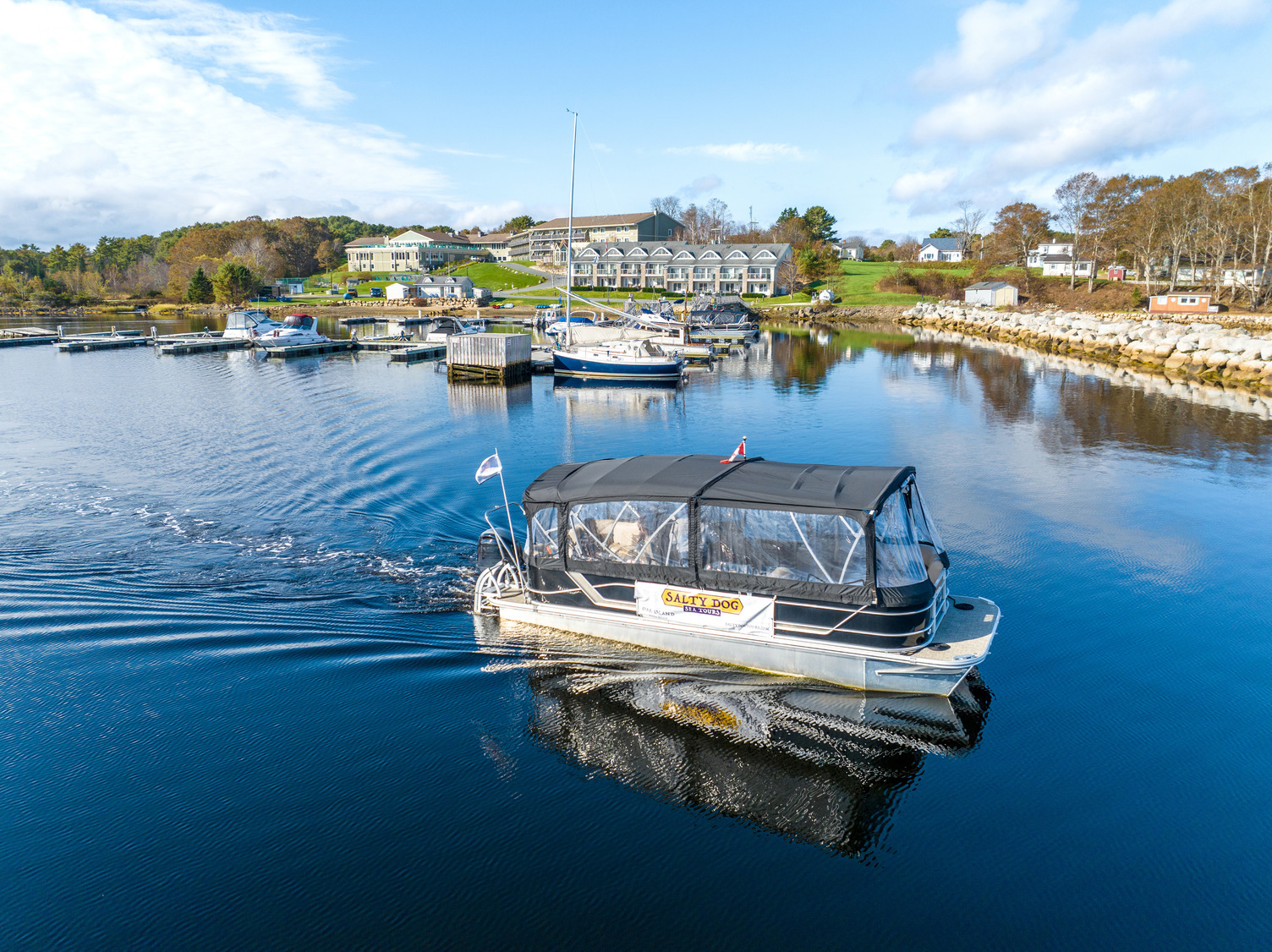 Photo shows a boat gliding along the water in front of the oak island resort on a sunny day